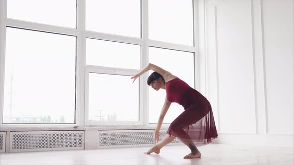 Dancer Woman Is Rehearsing a Dance in a Hall with Big Windows in Daytime