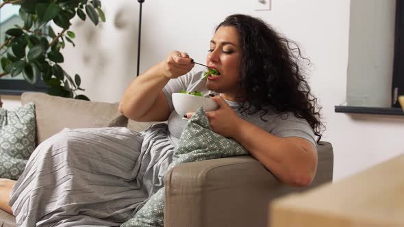 Smiling Young Woman Eating Vegetable Salad at Home