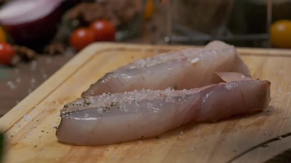 Professional chef sprinkles white fish steak with pepper