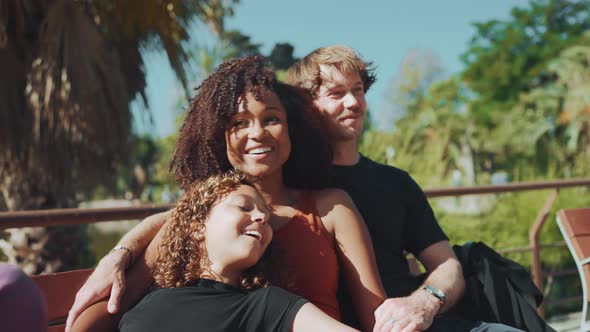 Smiling multiethnic family talking while sitting on the bench in the park