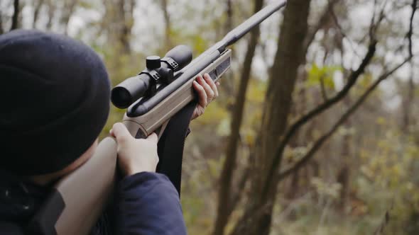 Hunter holding hunting rifle. Close up of young hunter holding hunting rifle aiming in forest
