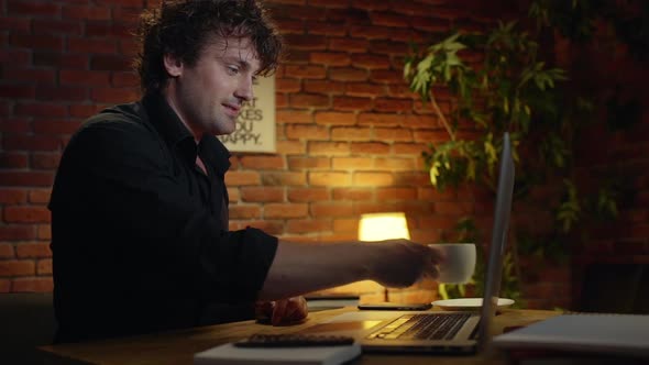 Young Successful Businessman Drinking Coffee Smiling Working in Office at Night