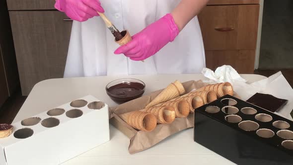 A Woman Smears Waffle Cones With Liquid Chocolate.