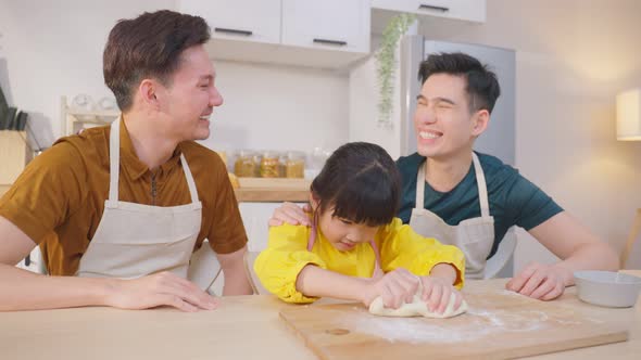 Asian LGBTQ gay family teach girl daughter kneads yeast dough, bake bakery in kitchen at house.