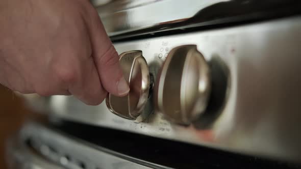 The Hand Turns on the Gas Stove in the Kitchen