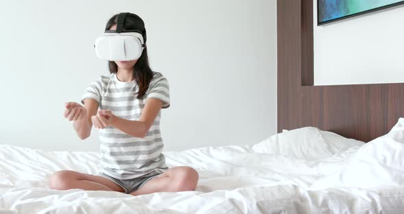 Woman wearing virtual reality device on bed