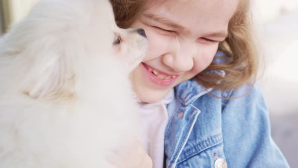 a Small and Happy Girl with a White and Fluffy Spitz Puppy