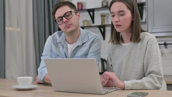 Serious Young Couple Working on Laptop in Living Room