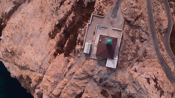 Top down drone shot of the lighthouse standing on the peninsula. Zoom out from the lighthouse to the