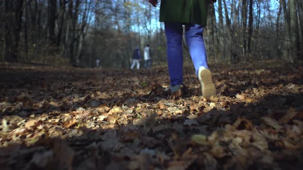 Middle-aged woman in sneakers and blue jeans walking in forest park Low view