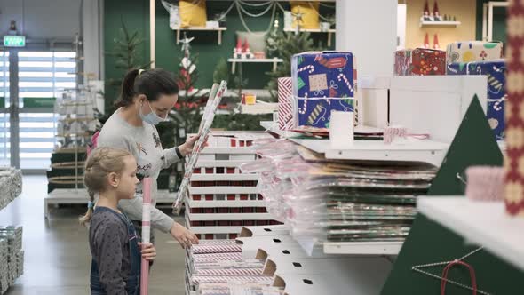 Woman with Daughter Choosing Xmas Wrapping Paper