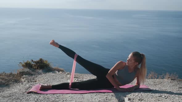 Girl Lies on Mat and Does Exercises with Rubber Bands, Trains Her Buttocks, Body