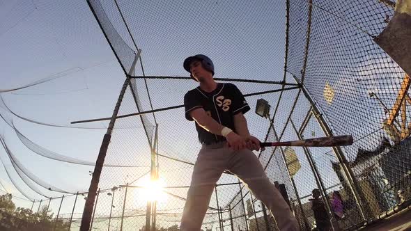 A baseball player practicing at the batting cages.