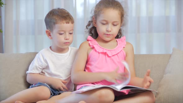 Cute Children,sister with a Younger Brother, Looking at a Book Magazine Textbook Dictionary Tablet