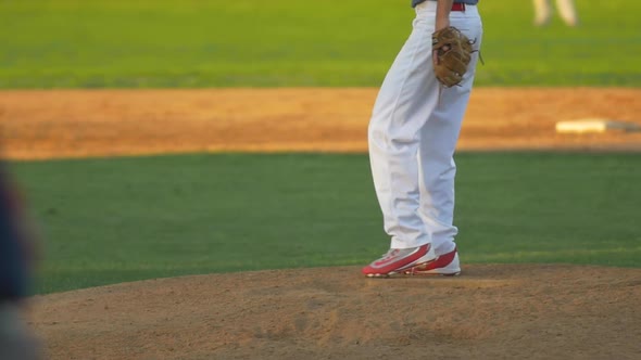 The pitcher at a baseball game throws the ball to the batter.