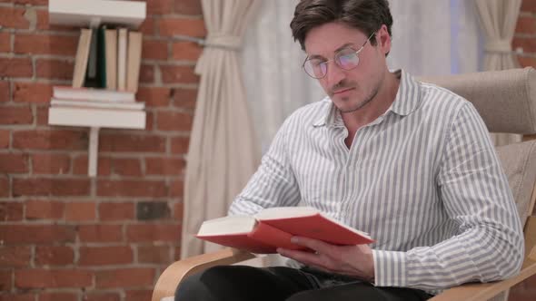 Middle Aged Man Reading Book on Sofa