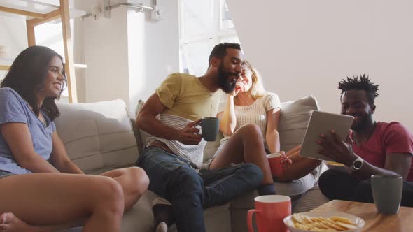 Two couples laughing together looking in the digital tablet