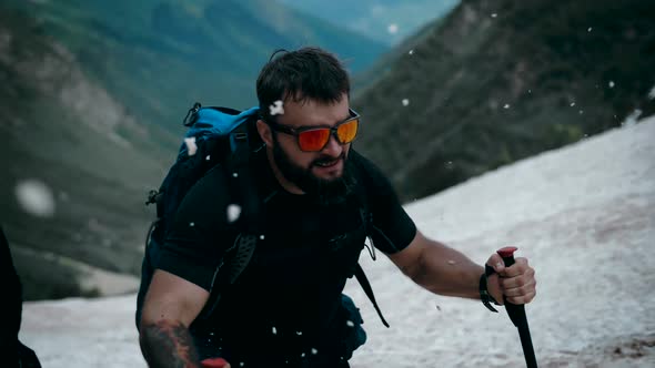 Mountaineer with a beard moves to the top of the snow-capped mountains in the snow of the glacier