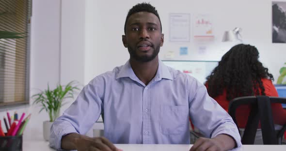 African american businessman sitting at desk, making video call in modern office