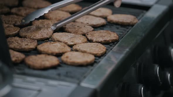 Close Up of Burgers Frying on a Grill. Chef Cooking Tossing and Flipping By Spatula Juicy Meat