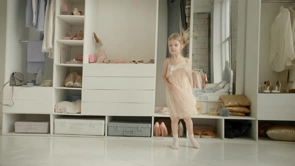 Dancing Little Girl Enjoy New Dress in Clothing Room on Backdrop of Wardrobe with Clothes