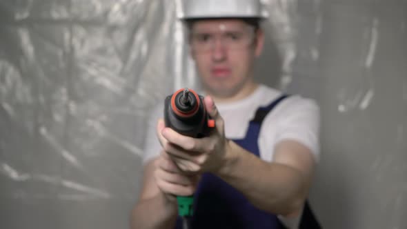 Builder in Blue Overalls and White Hard Hat Helmet and Glasses with Perforator