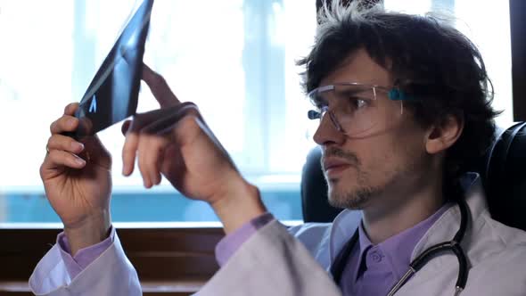 A doctor examines an X-ray of pneumonia of a patient with Covid-19 at a clinic. Coronavirus concept