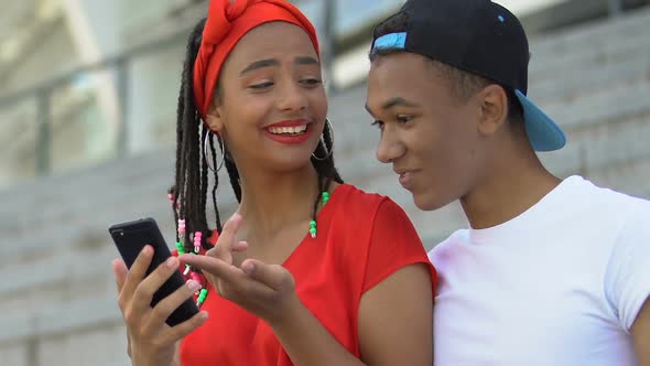 Black Teen Couple With Smartphone Looking Through Last Party Photos, Having Fun