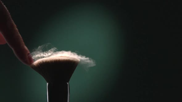 Makeup Brush With Powder Flying In The Air In Slow Motion On A Green Background