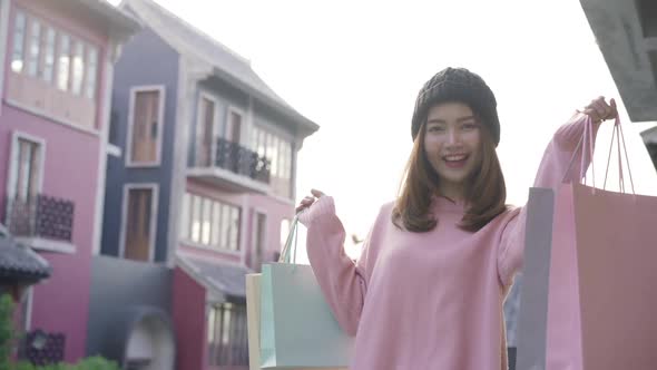 Beautiful shopaholic female holding shopping bags while walking for shopping outdoor.