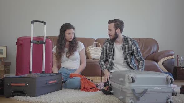 The Man and Woman Sitting on the Floor at Home in Front of Leather Sofa