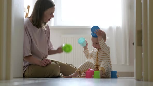 Little Baby Girl and Mommy Play with Colorful Toys at Home Sitting on Floor