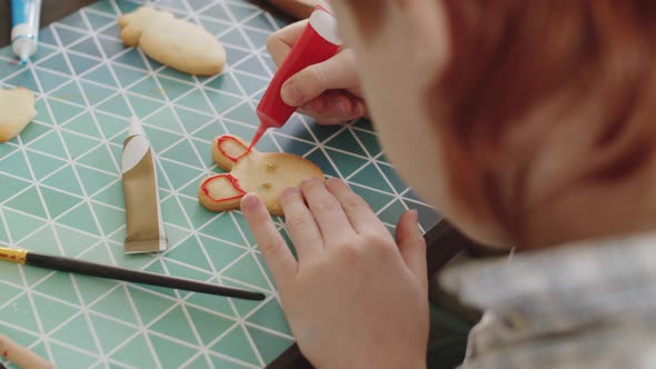 Kid Decorating Easter Cookie with Red Icing