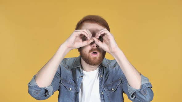 Redhead Man Searching with Handmade Binoculars Yellow Background