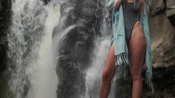 Longlegged Slim Young Female in Exotic Clothing Posing Near the Waterfall in a Mystical Image