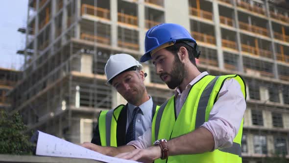 Male architect looking blueprint at construction site