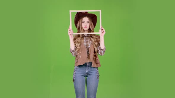 Cowgirl Is Holding a Wooden Frame and Posing As a Cowboy. Green Screen