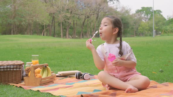 Happy little girl kid blowing soap bubbles playing alone in the park, Child having fun outdoor.