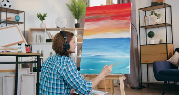 Artist Listening Music while Drawing Beautiful Picture on Canvas in His Own Home Workshop