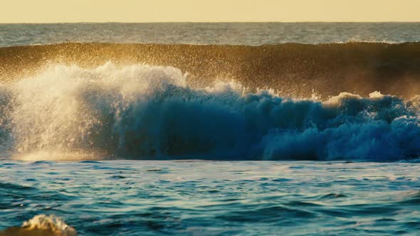 Ocean Wave Breaks on the Shore During Sunrise