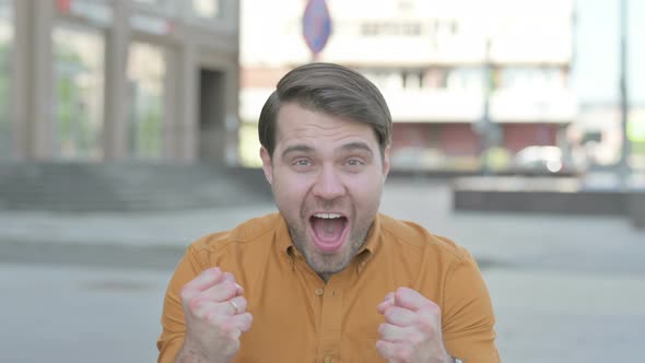 Portrait of Excited Young Man Celebrating Success Outdoor