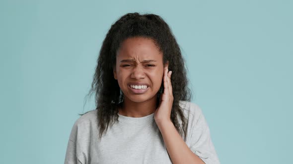 African American Teen Girl Suffering From Acute Toothache Touching Sore Cheek and Grimacing to