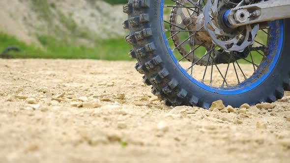 Close Up Wheel of Powerful Off-road Motorcycle Spinning and Kicking Up Dry Ground or Dust