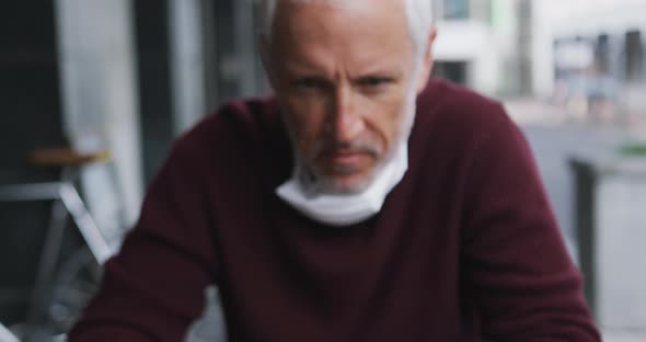 Caucasian man out and about in a coffee wearing a face mask against coronavirus