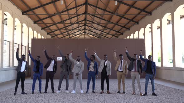 Black businessmen in suits with raised arms