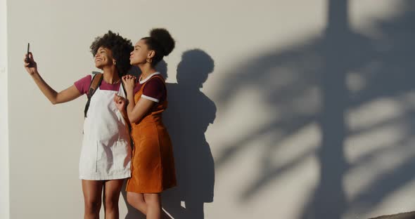 Two mixed race women taking picture on street