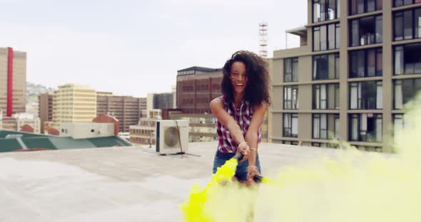 Fashionable young woman on urban rooftop using a smoke grenade