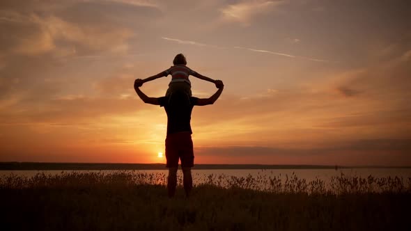 Silhouettes of Dad and Son Playing Rejoicing in Field at Sunrise