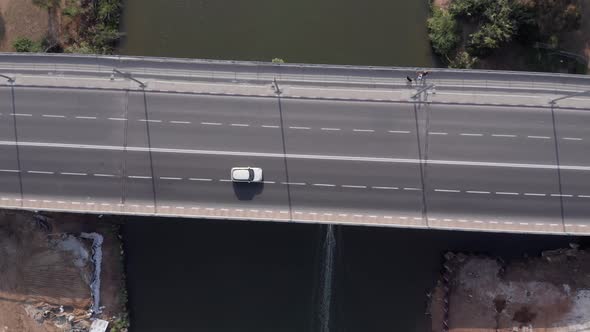 Small White boat heading upstream of the Yarkon river passing under city bridges.