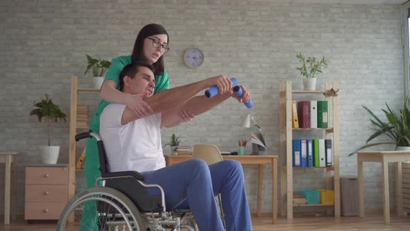 Girl Nurse Helps in the Rehabilitation of a Disabled Person in a Wheelchair